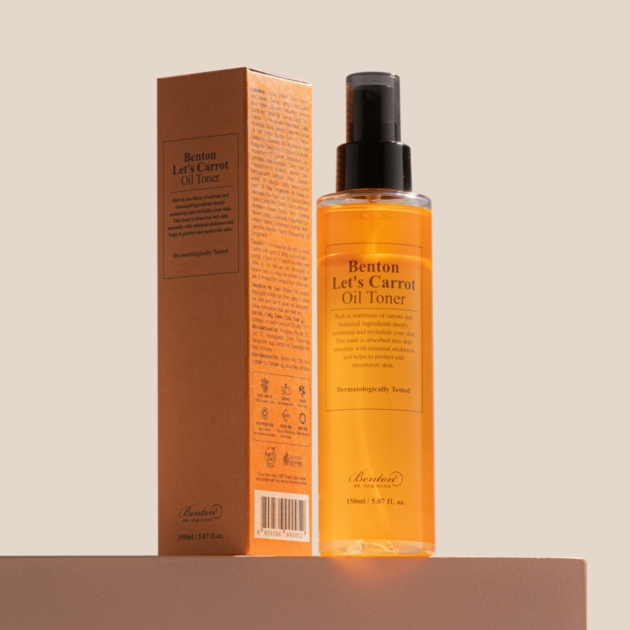 Benton kasvovesi, kuva avaamattomasta tuotteesta, pitkulainen muovipullo, päässä painettava suihkepää, kuvassa myös pahvipaketti (Let's Carrot Oil Toner)